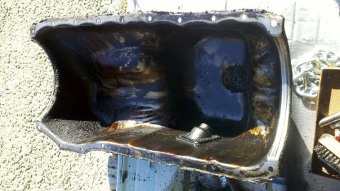 1978 Ford Bronco - This is a close-up of a heavily soiled oil pan, likely removed for cleaning or replacement.