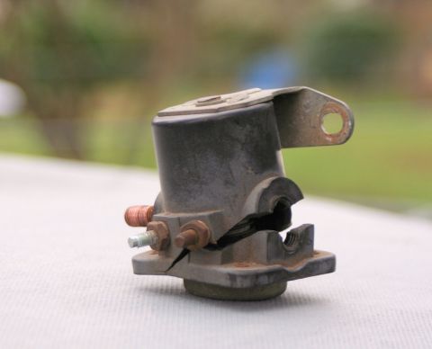 1976 Ford Ranchero - A cracked battery solenoid is shown, copper and steel terminals and a mounting bracket.