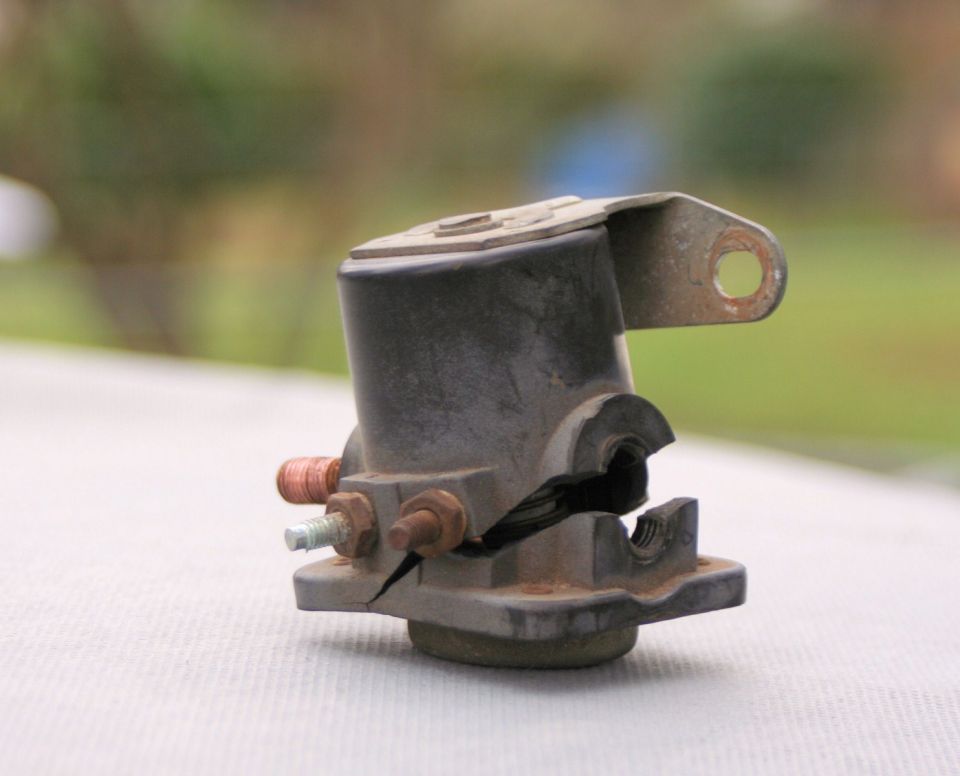 Cracked black battery solenoid with copper and steel terminals