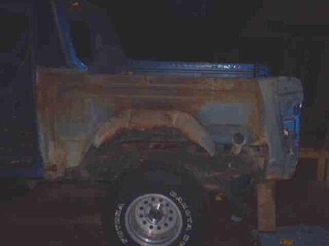 1990 Ford Bronco - This 1980s Ford Bronco shows significant rust on its rear quarter panel, indicating it is likely undergoing restoration or repair.