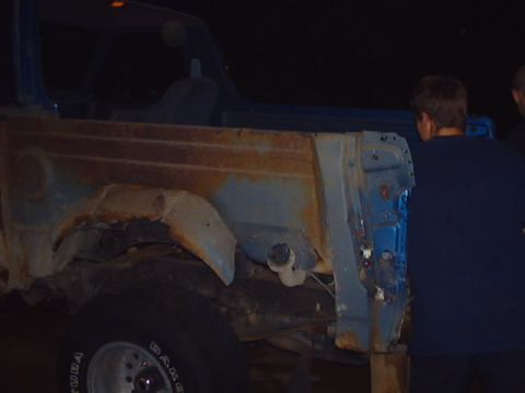 1990 Ford Bronco - This blue SUV's body panel displays extensive rust and damage, indicating a need for repair or restoration.