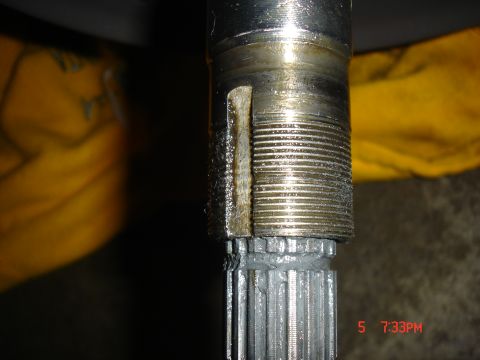 Close-up of a splined shaft with a damaged keyway and threaded section, covered in grease