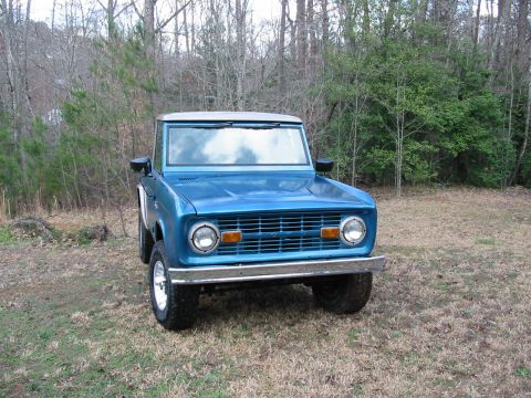 1969 Ford Bronco - A blue 1969 Ford Bronco is parked outdoors in a grassy, wooded area.