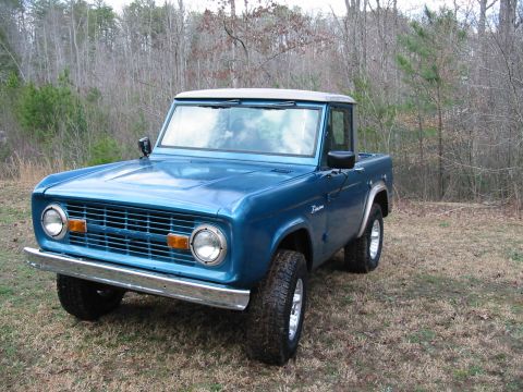 1969 Ford Bronco - This 1969 Ford Bronco is shown in a three-quarter front view, parked on a grassy area with trees in the background.