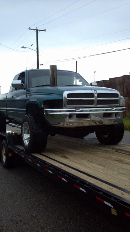 1997 Dodge 2500 - Green Dodge 2500 pickup truck with a tall exhaust pipe is loaded onto a flatbed trailer.