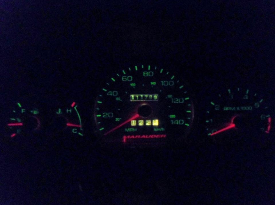car's dashboard with speedometer showing 122 mph, odometer at 111799, and tachometer
