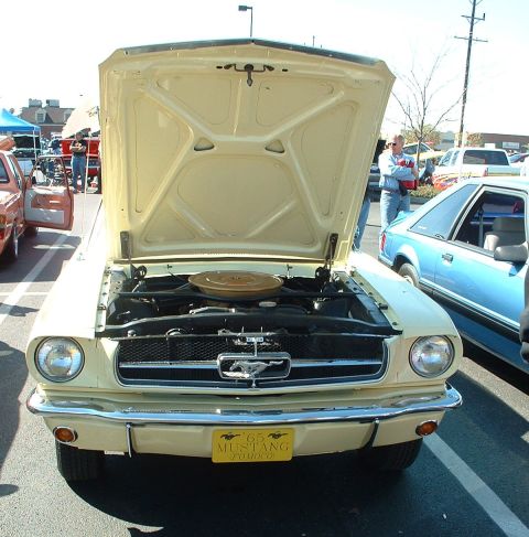 1995 Ford Crown Victoria - A classic yellow 1965 Ford Mustang is displayed with its hood open, revealing the engine compartment.
