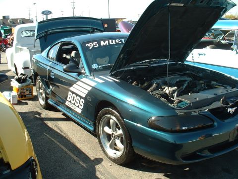 1995 Ford Crown Victoria - A 1995 Ford Mustang GT is displayed with its hood open, next to a white pickup truck.