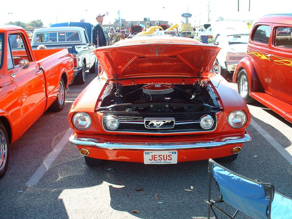Orange Ford Mustang with hood open, parked next to other classic cars