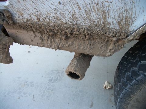1996 Ford Bronco - A vehicle's exhaust pipe and tire are heavily coated in mud, suggesting recent off-road use.
