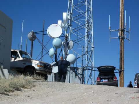 1996 Ford Bronco - A man stands by a cell tower with a truck and a car parked nearby.