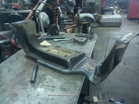 1979 Ford Bronco - A custom fabricated metal bracket, likely for a vehicle modification, sits on a workbench with various tools and materials.