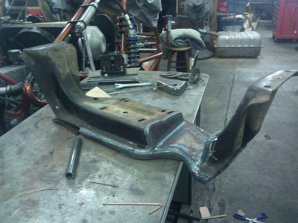 Custom metal bracket with welds on a workbench, copper wire and tools nearby