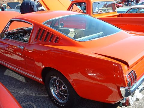 1995 Ford Crown Victoria - Side view of an orange 1965 Ford Mustang coupe at a car show.