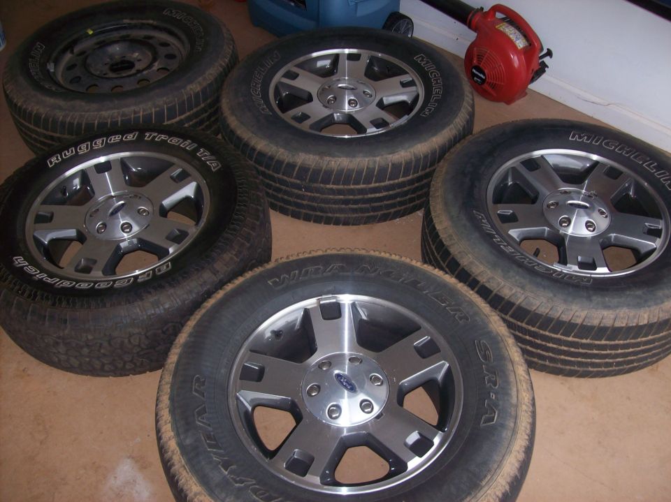 Five tires on the ground, four with custom Ford rims, one with a steel rim.