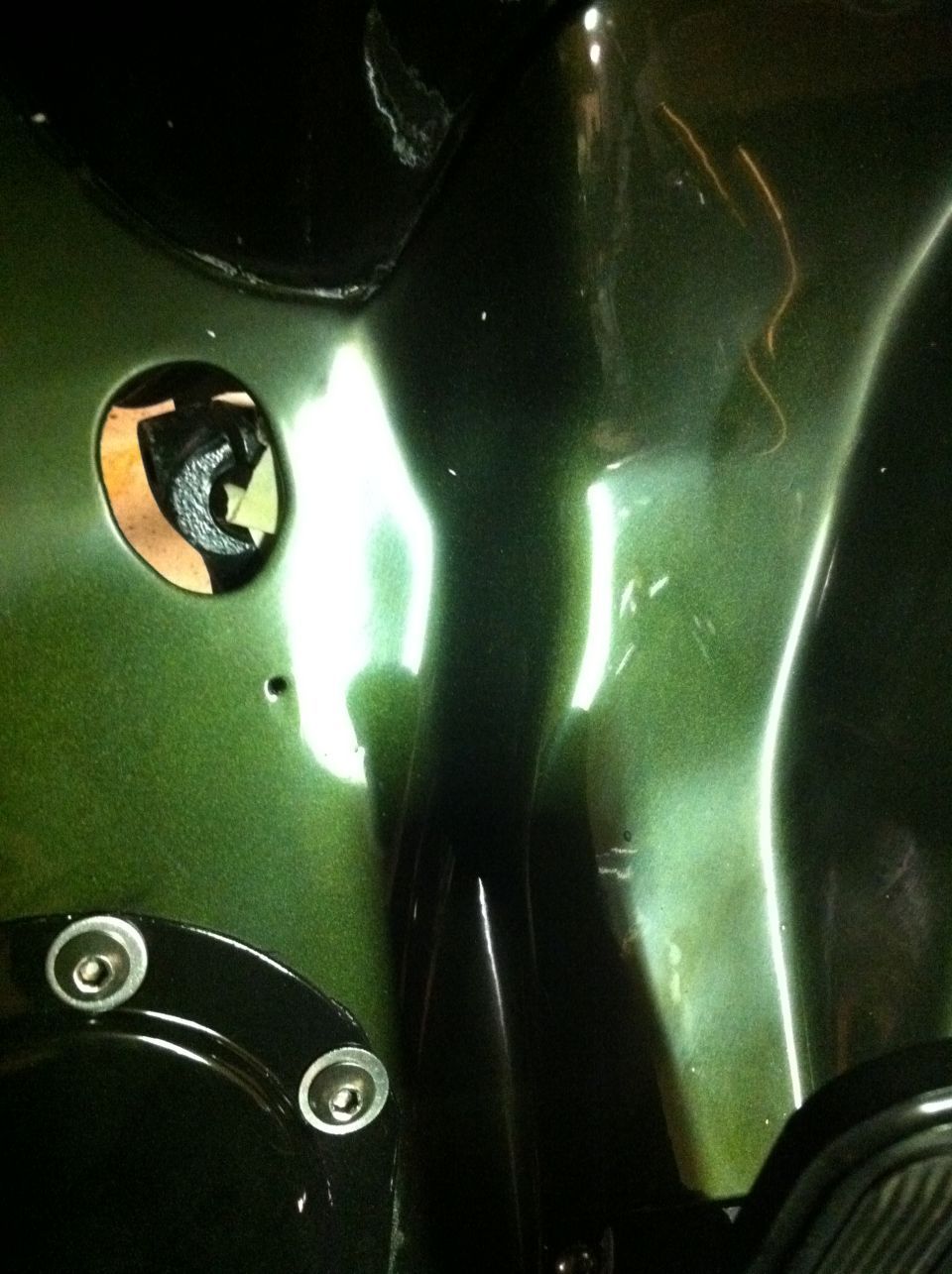 Green metallic vehicle body panel with a circular cutout and mesh insert.