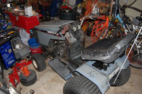 2010 Kawasaki BAYOU 220 - A Craftsman riding mower is seen in a garage filled with tools and bicycles.