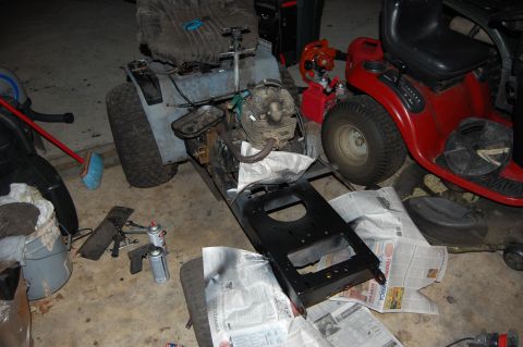 2010 Kawasaki BAYOU 220 - Lawn tractors in a garage, one being worked on with parts laid out on newspaper.