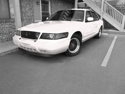2000 Mercury Grand Marquis - A white 2000 Mercury Grand Marquis is parked in a lot, viewed from the front three-quarter angle.