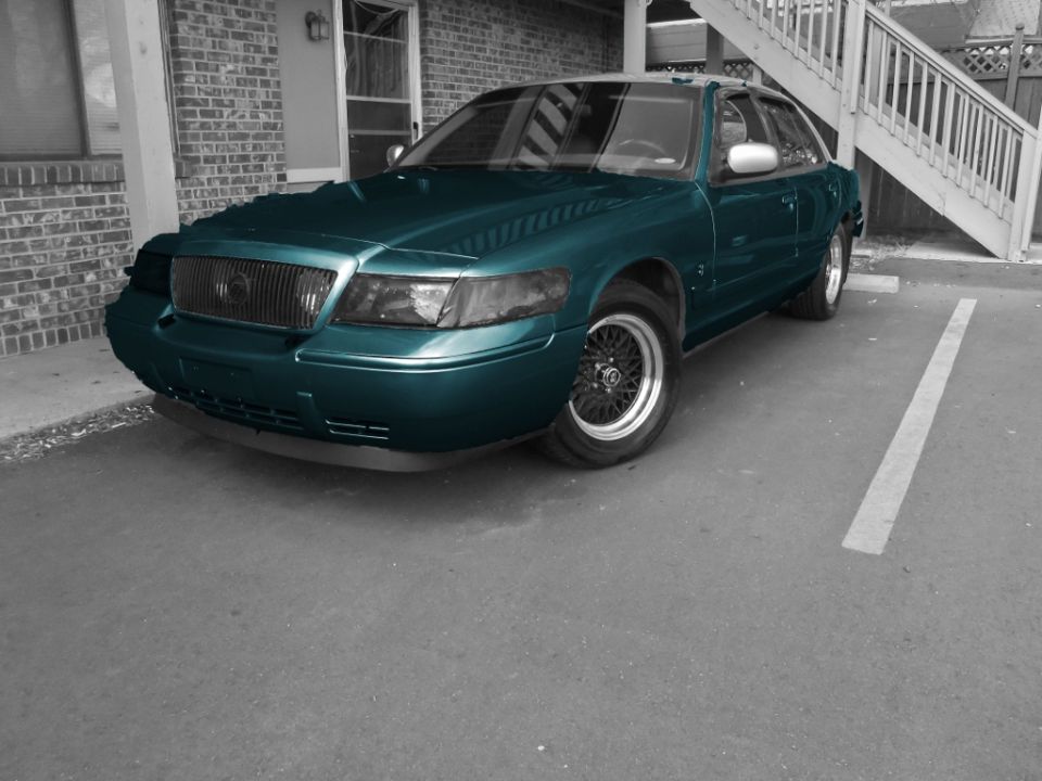 teal sedan parked in a spot, front quarter view