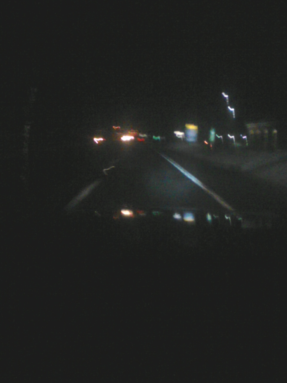 Driving on a highway at night with lights from other cars and signs visible