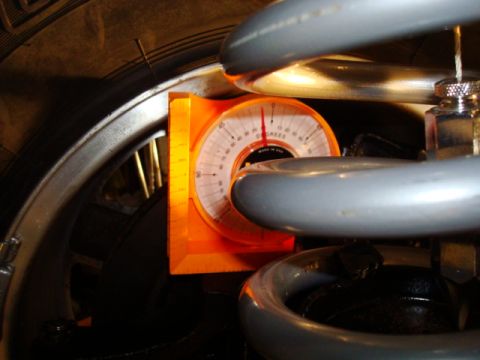 1995 Ford Bronco - An orange alignment gauge is positioned on a vehicle's suspension system, close to the tire.