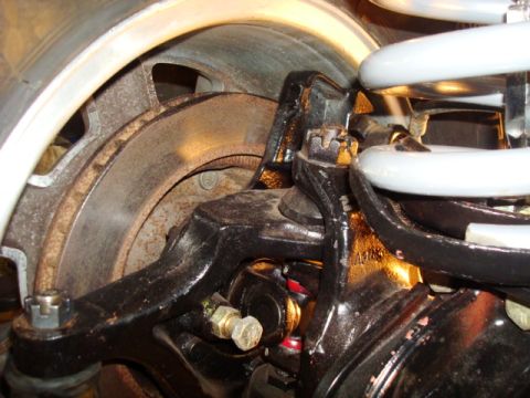 1995 Ford Bronco - Close-up view of the suspension and braking system of a 1995 Ford Bronco, showing the brake rotor, coil spring, and various black-painted s…