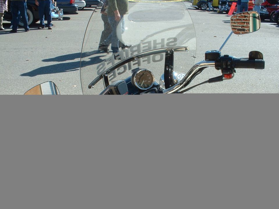 Handlebar view of a motorcycle with 'Sheriff's Office' windshield at a car show