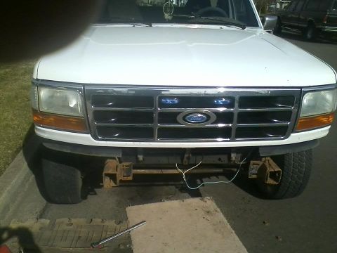 1992 Ford Bronco - Front view of a white 1992 Ford Bronco with a chrome grille and exposed bumper mounts.