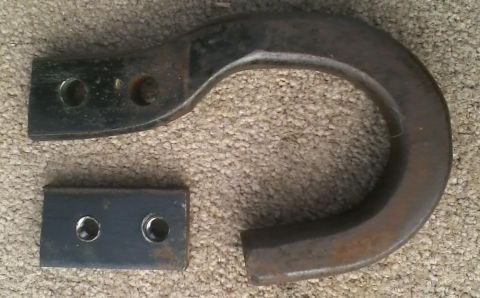 1992 Ford Bronco - A rusty tow hook and its mounting plate are shown on a carpeted surface.
