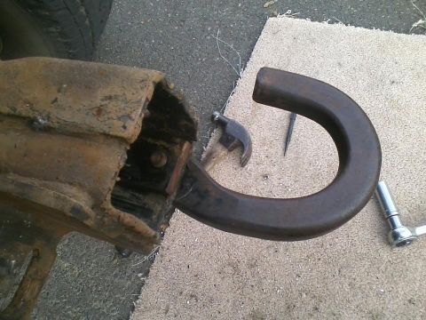 1992 Ford Bronco - Close-up of a rusted tow hitch part with tools on the ground.