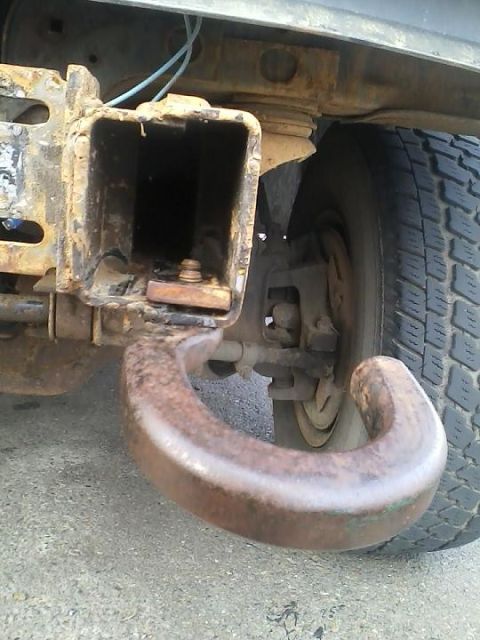 1992 Ford Bronco - Close-up of a heavily rusted tow hook and a vehicle's tire, showing wear and tear.