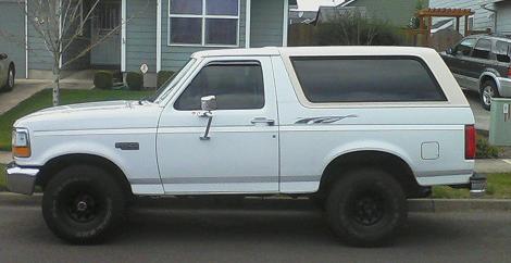 1992 Ford Bronco - Side profile of a white 1992 Ford Bronco parked on a residential street.