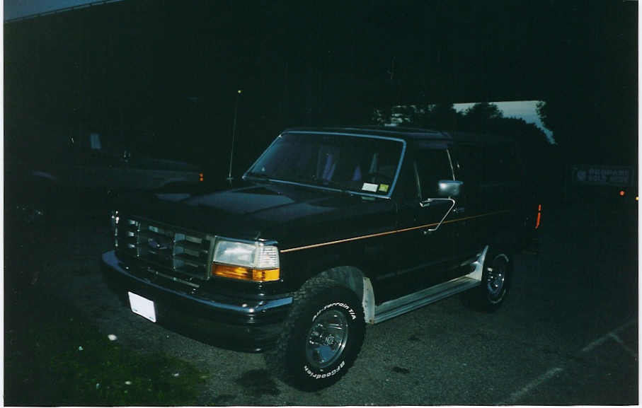 Black Ford F-150 pickup truck parked outside at night. It has a chrome grille and orange turn signals