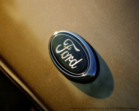 2005 Ford Crown Victoria - Ford emblem on a gold car, likely a 2005 model.