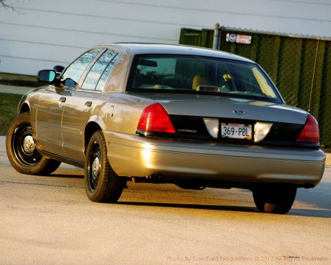 2005 Ford Crown Victoria - This gold Ford Crown Victoria is shown from the rear, parked on a paved surface.
