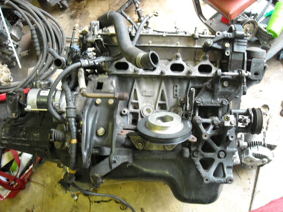 Engine block with alternator, hoses, and pulleys attached