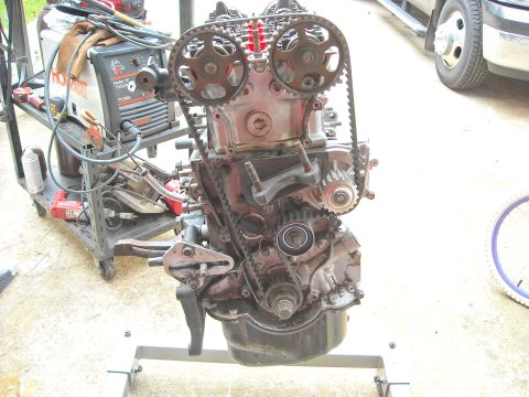 1979 Ford F-150 - Engine assembly on a stand with various mechanical components and tools nearby.