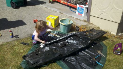 1978 Ford Bronco - A young child is cleaning a car part with a brush and soap in a driveway.