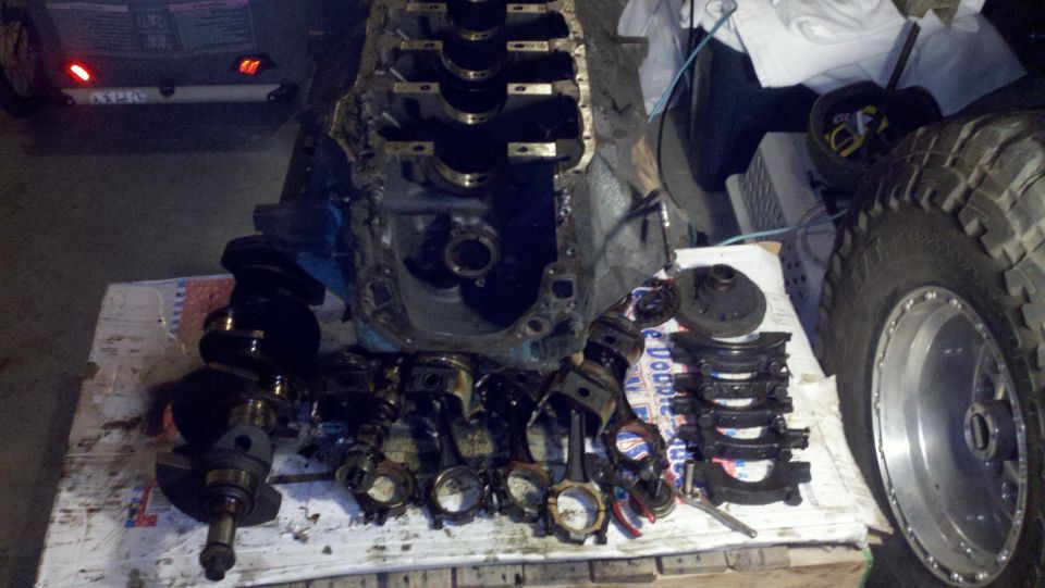 Engine block, crankshaft, pistons, and connecting rods laid out on a surface