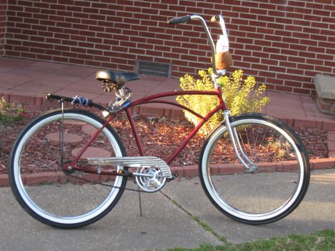 1994 Ford Bronco - A red cruiser bicycle with chrome accents and whitewall tires is parked outside a brick building.