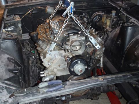 1978 Nissan 300ZX - An engine is suspended by chains and a hoist, ready for installation into a vehicle's engine compartment.
