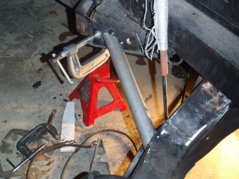 1978 Nissan 300ZX - Close-up view of a vehicle's frame being repaired, showing clamps, a jack stand, and welding apparatus.