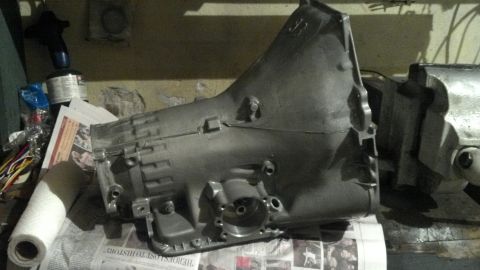 1979 Ford Bronco - A transmission casing is held in a vise, with newspapers visible underneath.