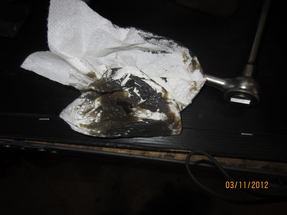 Dirty paper towel with oil stains next to a ratchet wrench. Date stamp reads 03/11/2012
