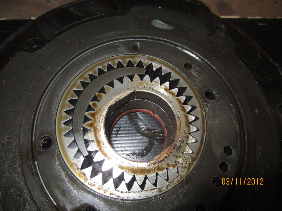 Close-up of a transmission part with two sets of gears, one inside the other, showing wear and oil residue