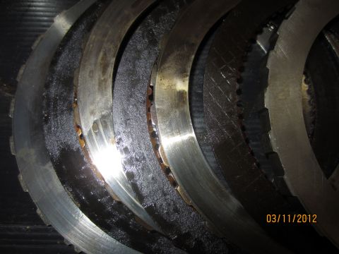 1979 Ford Bronco - Close-up view of several worn transmission clutch plates, indicating a need for replacement.