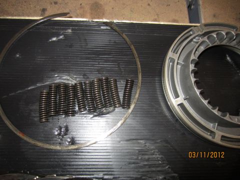 1979 Ford Bronco - Transmission parts, including clutch springs and a drum, are laid out on a black surface.