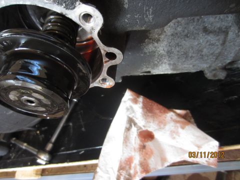 1979 Ford Bronco - A close-up view of a vehicle's transmission component, with a paper towel nearby to absorb dripping fluid.