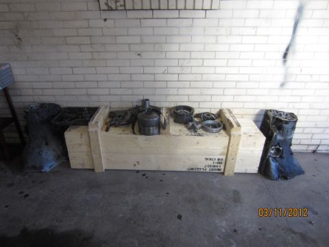 1979 Ford Bronco - Various transmission parts and housings are laid out on wooden crates against a brick wall.